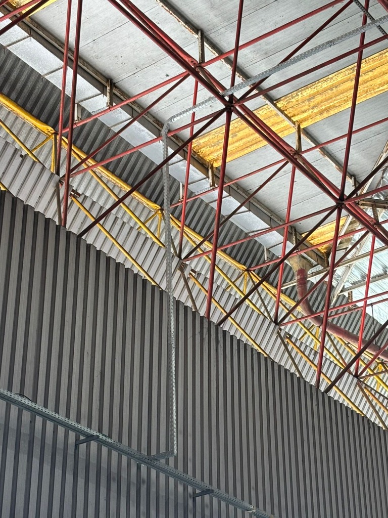 Eletrocalha vertical instalada em parede metálica de um galpão.